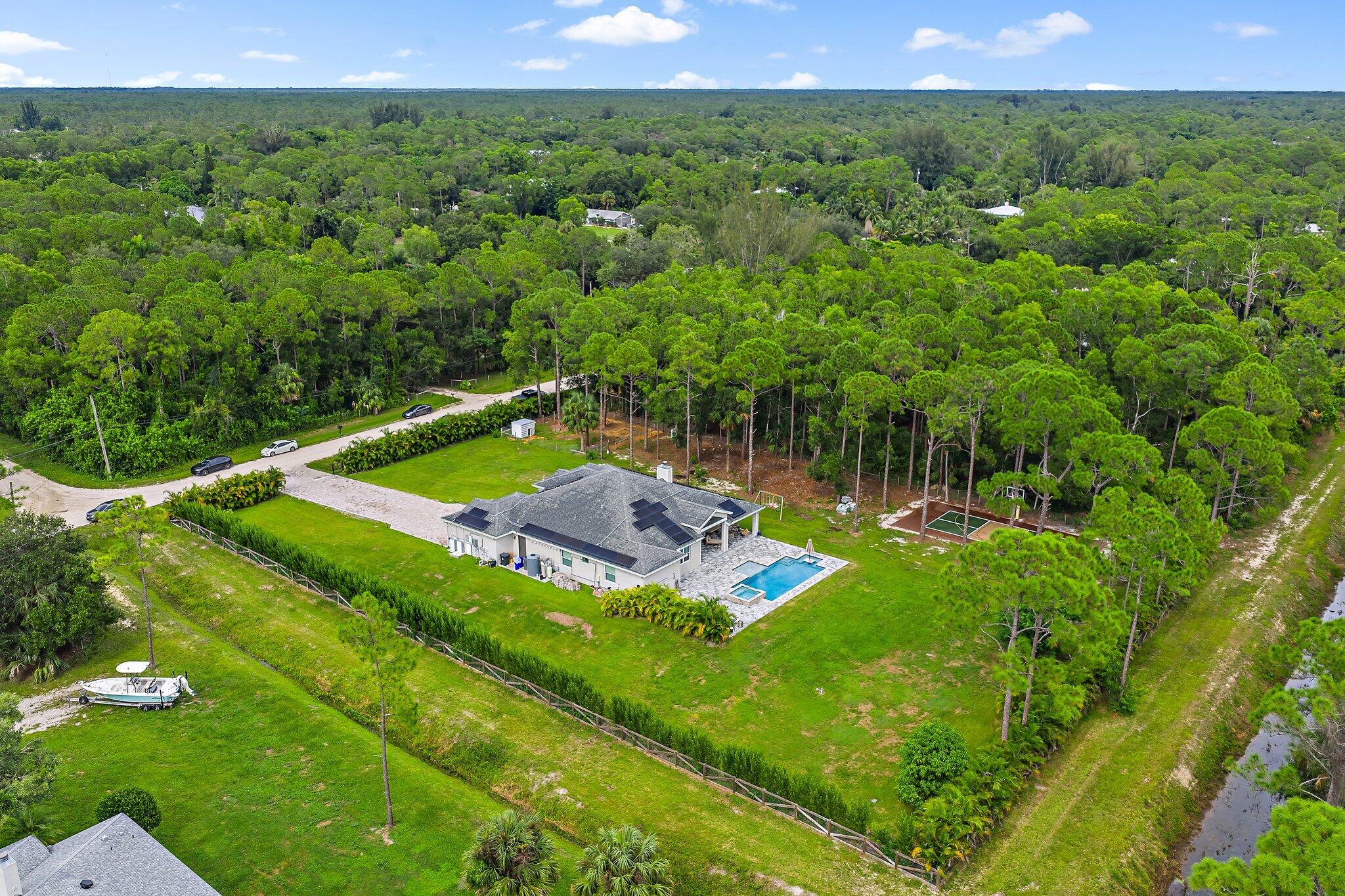 12216 175th Road North Jupiter, FL 33478 - Photo 55 of 57 a view of a backyard with lawn chairs floor to ceiling fan yard and outdoor kitchen view
