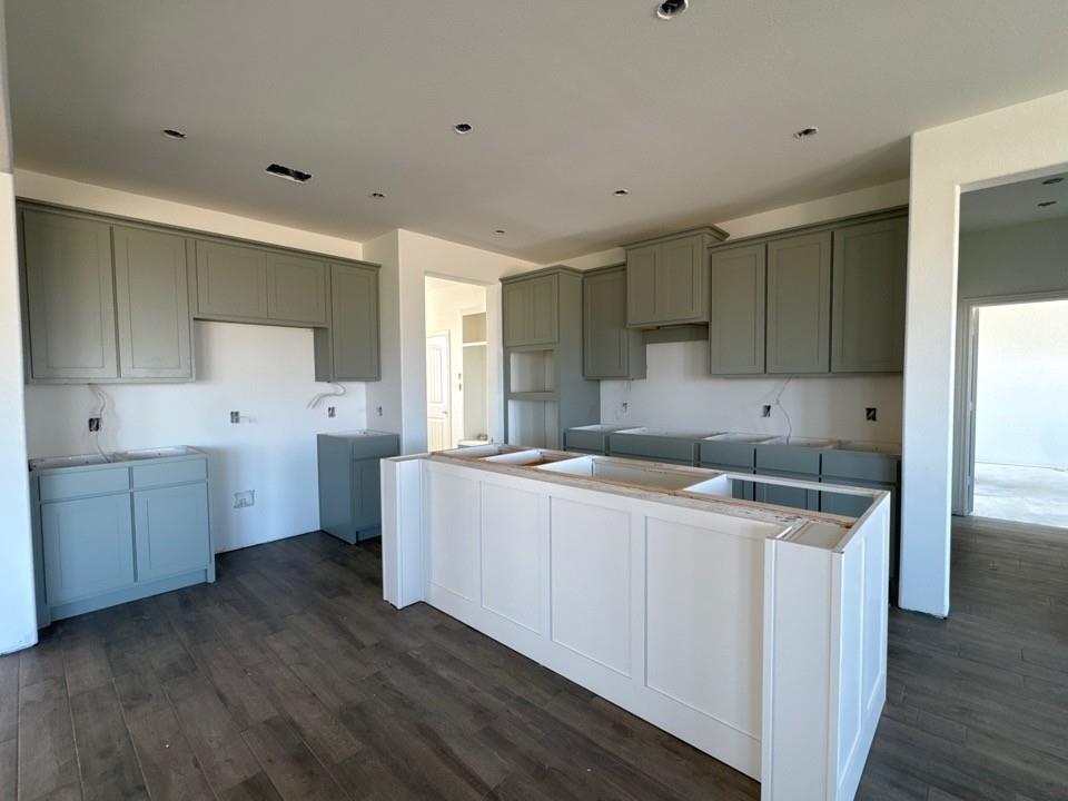 130 Fossil Canyon Drive Rhome, TX 76078 - Photo 6 of 15 a kitchen with a wooden floor and white cabinets