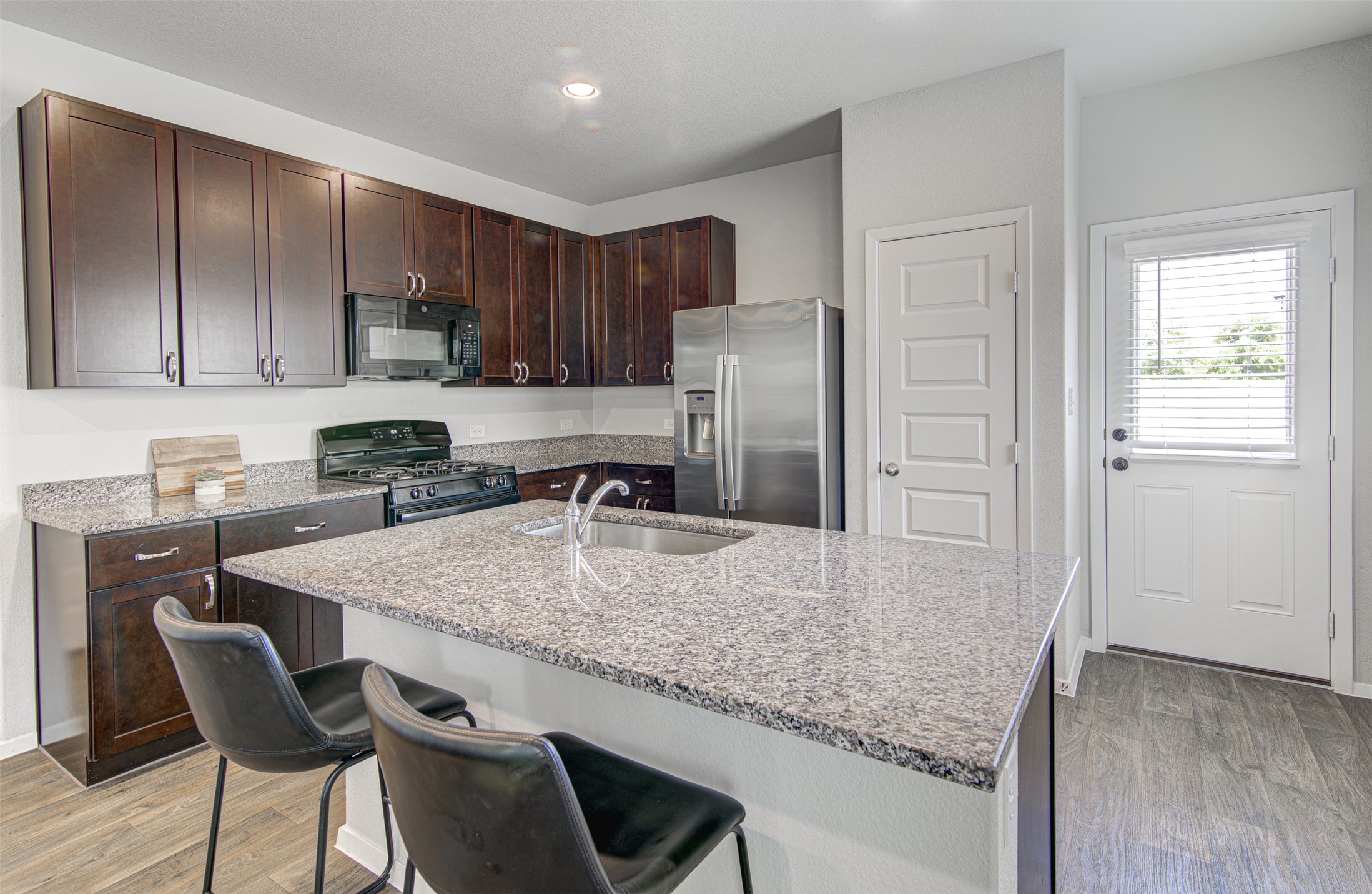 156 Tillage Road Elgin, TX 78621 - Photo 8 of 25 A well-appointed kitchen features a central island, granite countertops, and rich cabinetry.
