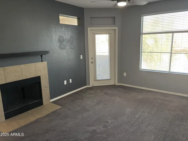 an empty room with windows and fireplace