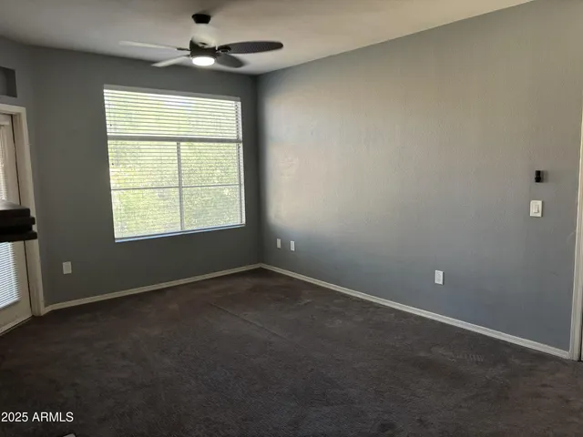 en empty room with windows and chandelier fan
