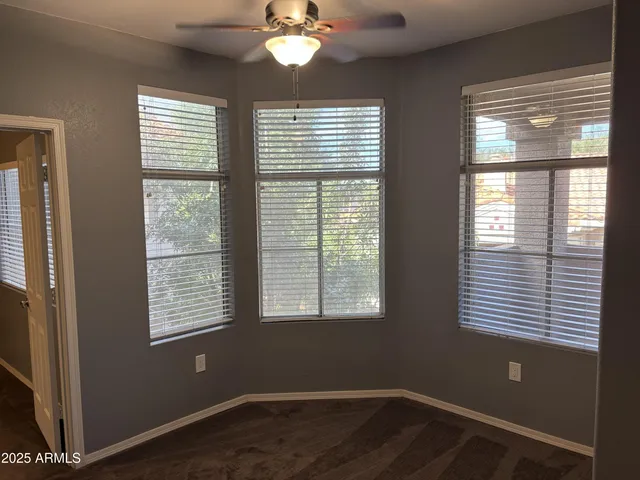 a view of an empty room with wooden floor and windows