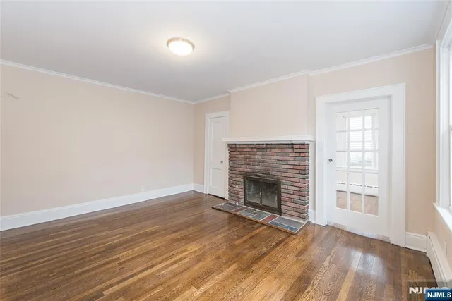 an empty room with wooden floor fireplace and windows