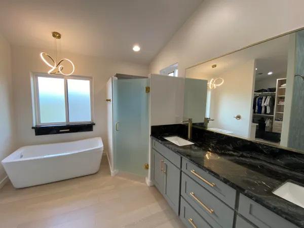 a bathroom with a granite countertop tub sink and mirror