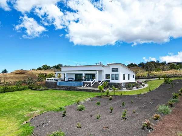 a front view of a house with a garden and trees