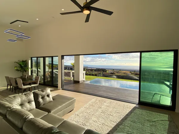 a living room with furniture floor to ceiling window next to a yard