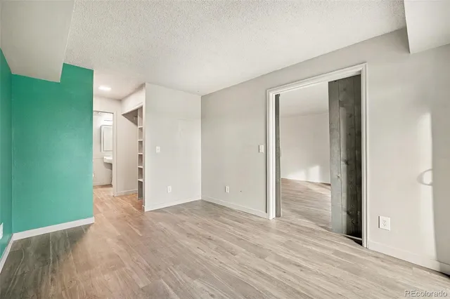 an empty room with wooden floor & windows