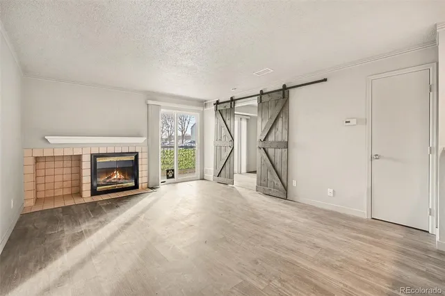 a view of an empty room with wooden floor fireplace and a window