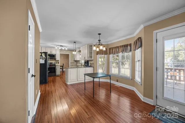 a living room with stainless steel appliances wooden floor and a large window