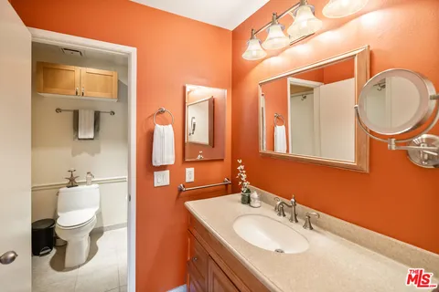a bathroom with a granite countertop toilet sink and mirror