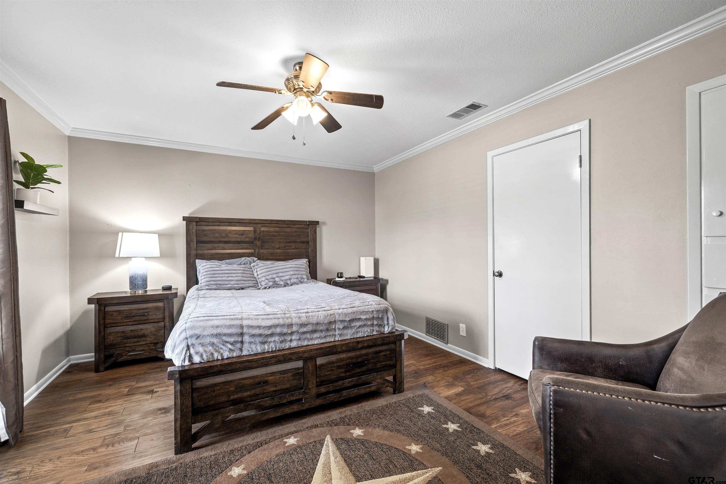 8235 Baylor Drive Tyler, TX 75703 - Photo 14 of 31 a bedroom with a bed and wooden floor