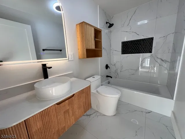 a bathroom with a toilet a sink a mirror and bathtub