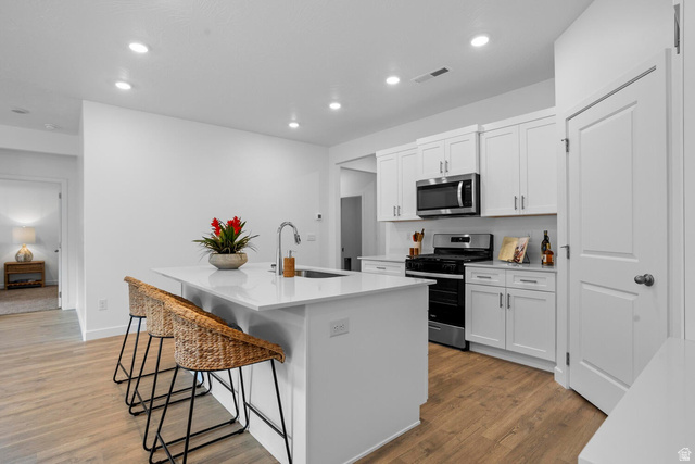 1624 South Staircase Way, Unit 4183 Washington, UT 84780 - Photo 18 of 47 Modern kitchen featuring white shaker cabinetry, stainless steel appliances, a center island with sink, recessed lighting, and wood-finish flooring
