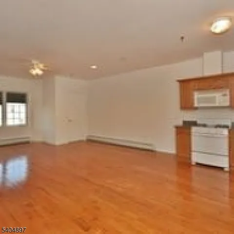 a view of empty room with kitchen and window