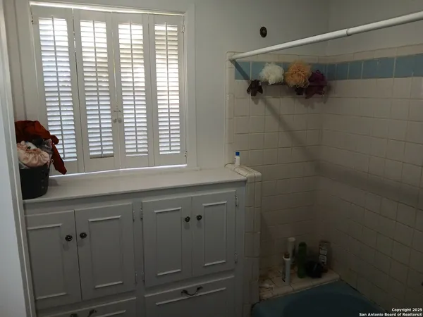 a bathroom with a bathtub a shower and a window