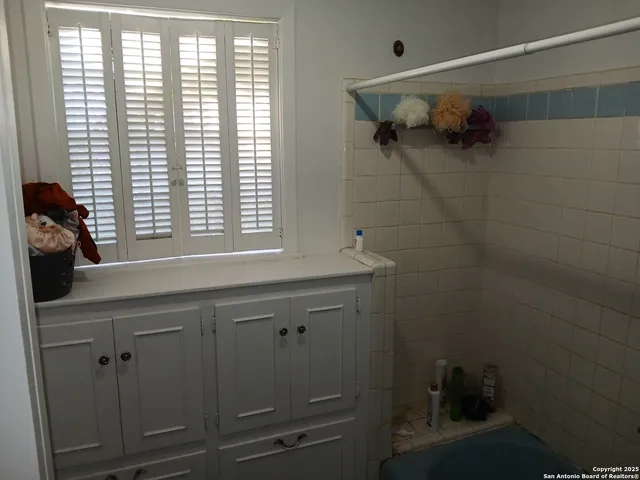 a bathroom with a bathtub a shower and a window