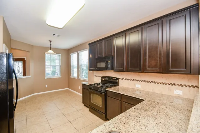 a kitchen with granite countertop stainless steel appliances a stove sink and refrigerator