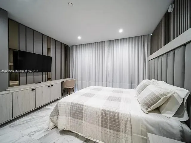 a bedroom with a large bed and a flat screen tv
