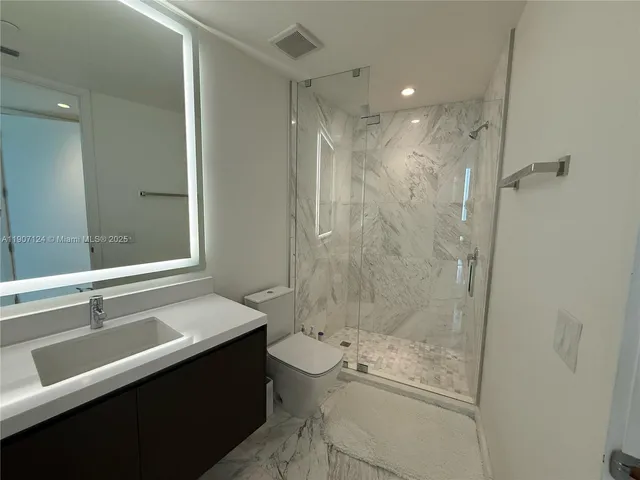 a bathroom with a shower sink vanity mirror and toilet