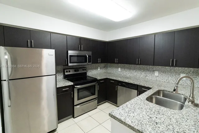 a kitchen with granite countertop a refrigerator and a sink