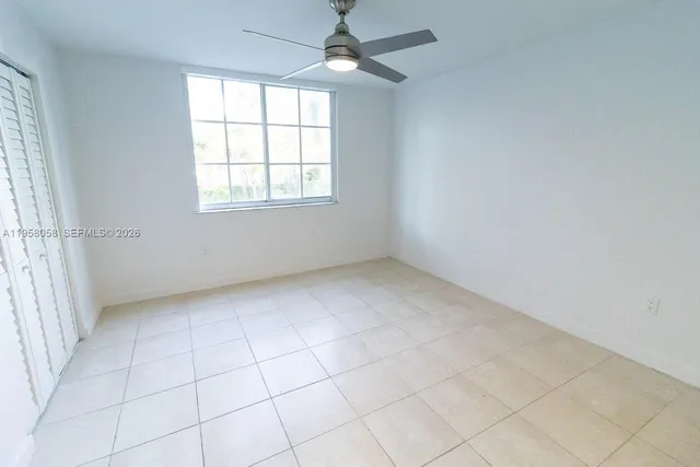 an empty room with chandelier fan and windows