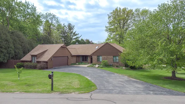 a view of a house with a big yard plants and large trees