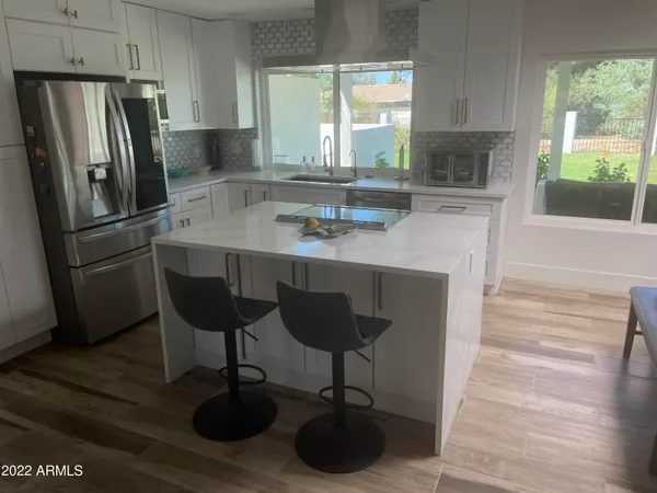a kitchen with stainless steel appliances a dining table chairs and a large window