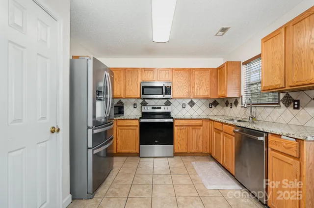 a kitchen with stainless steel appliances granite countertop a refrigerator and a stove top oven
