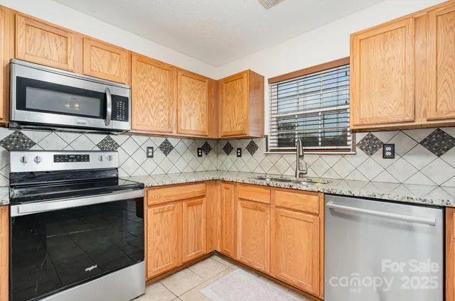 a kitchen with granite countertop cabinets stainless steel appliances a sink and window