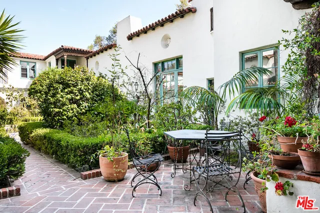a view of a patio with table and chairs potted plants and large tree
