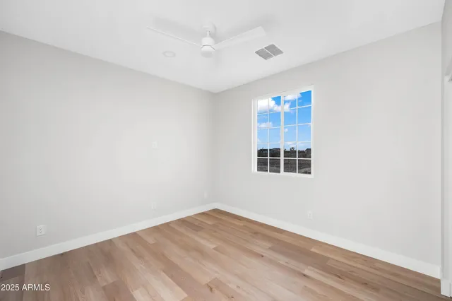 an empty room with wooden floor & closet and windows