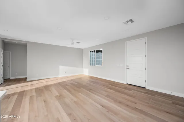 a view of empty room with wooden floor and fan