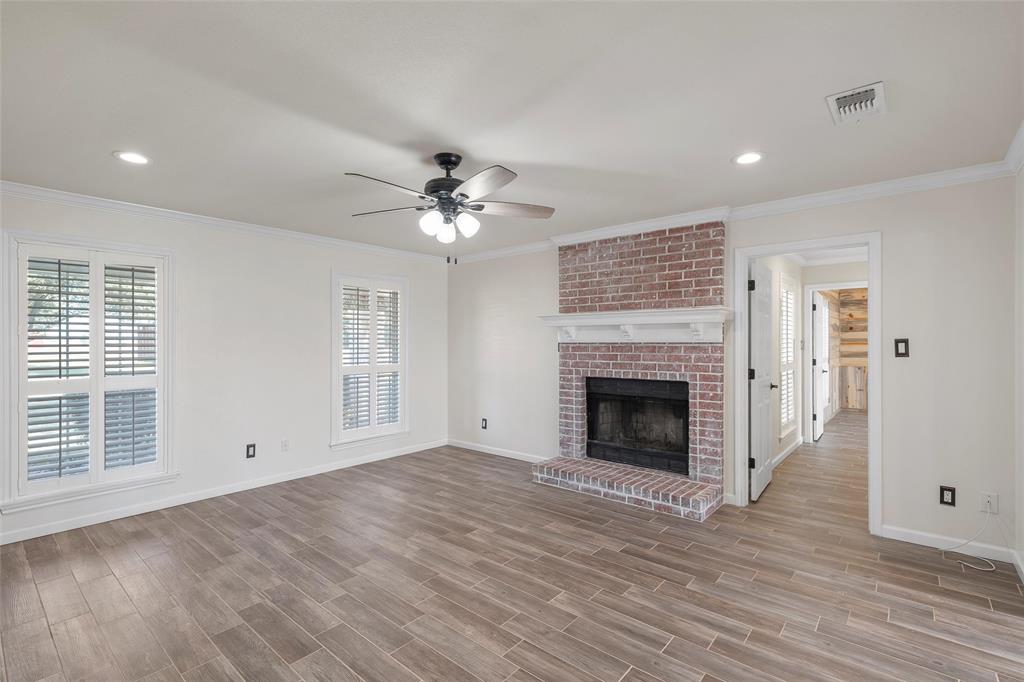 5112 Old Caufield Ranch Road McGregor, TX 76657 - Photo 12 of 38 Unfurnished living room featuring a brick fireplace, ornamental molding, recessed lighting, ceiling fan, and plenty of natural light
