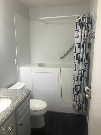 a bathroom with a granite countertop toilet and a shower