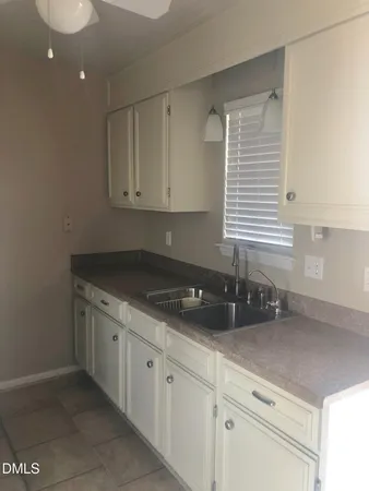 a kitchen with granite countertop white cabinets and a sink