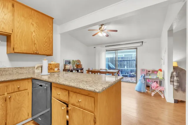 a kitchen with stainless steel appliances granite countertop a sink dishwasher and a stove with wooden floor