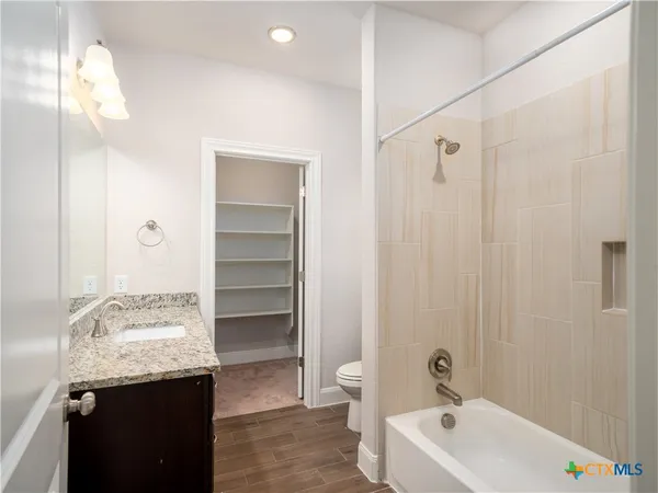 a bathroom with a granite countertop sink a toilet and shower