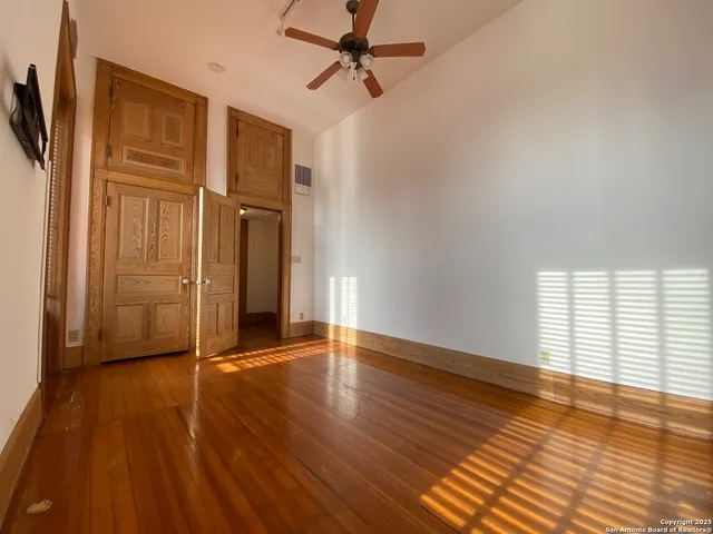 an empty room with wooden floor door and windows