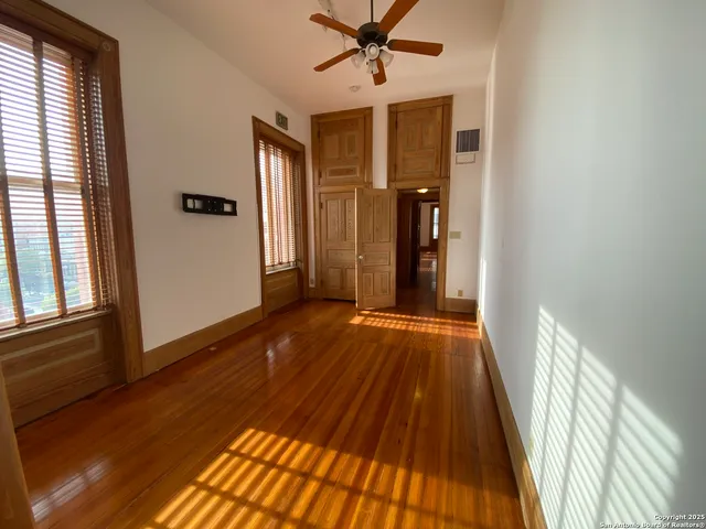 a view of a room with wooden floor staircase and a ceiling fan