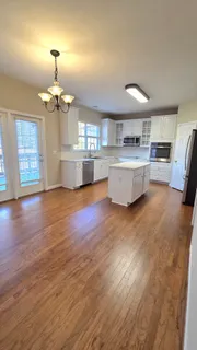 a kitchen with stainless steel appliances a sink a stove a refrigerator cabinets and a wooden floor