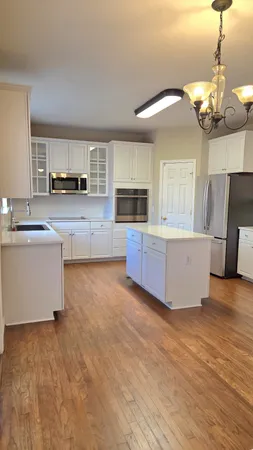 a view of a kitchen with kitchen island a sink wooden floor and a large window