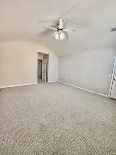 a view of an empty room with chandelier fan and window
