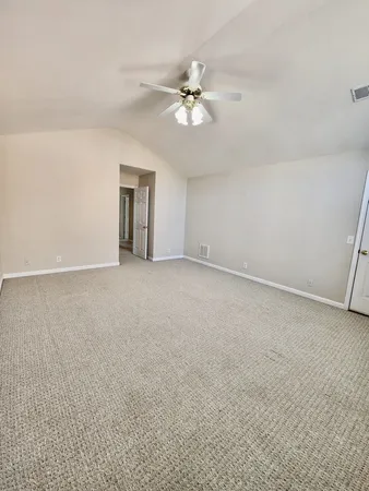 a view of an empty room with chandelier fan and window
