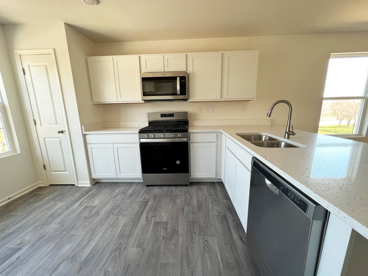 2241 Sassafras Way, Unit F Wonder Lake, IL 60097 - Photo 4 of 46 a kitchen with stainless steel appliances granite countertop a sink a stove a microwave and wooden floors