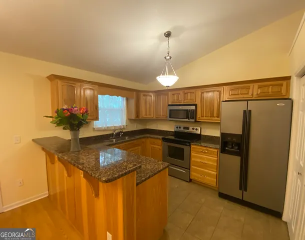 a kitchen with stainless steel appliances granite countertop a sink a stove and refrigerator