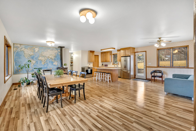 887 Village Way Alpine, UT 84004 - Photo 14 of 28 Dining room featuring wallpapered walls, a wood stove, a ceiling fan, and light wood finished floors