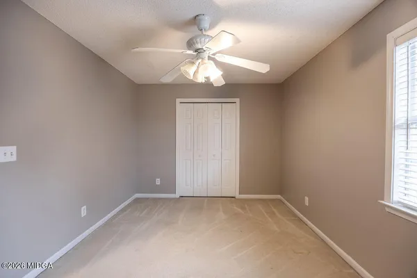 an empty room with windows and fan