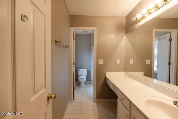 a en suite bathroom with a granite countertop sink a toilet and shower