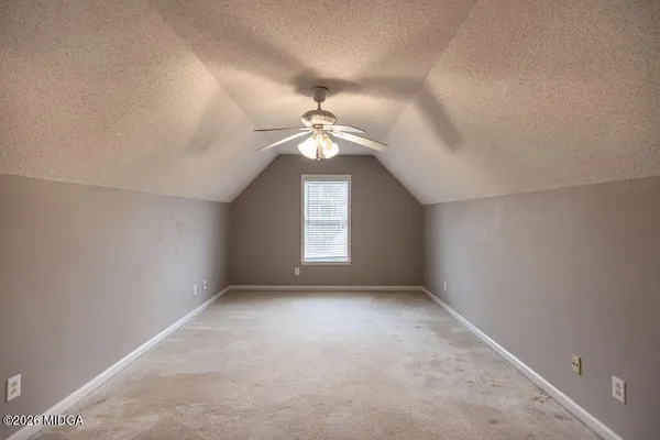 an empty room with a chandelier fan and windows