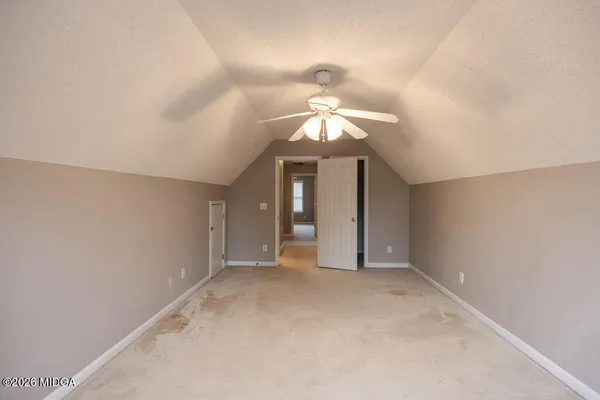 an empty room with a chandelier fan and windows